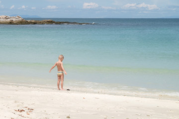 Fototapeta na wymiar European boy age 3-5 years old stands on the beach, Opening arm.