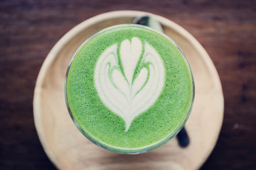 Matcha green tea latte art on wooden table.