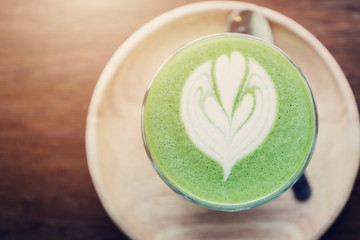 Matcha green tea latte art on wooden table.