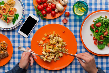 Woman eating healthy food on checkered tablecloth background, top view.