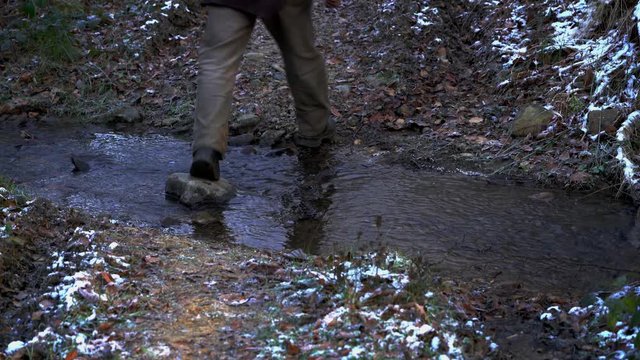 Man crosses the creek in the winter wood - (4K)