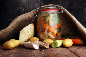 Jar with variety of pickled vegetables. Broth, Carrots, field garlic, parsley in glas. Preserved...