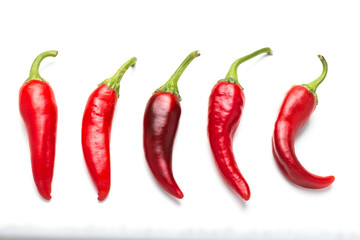 A group of five bitter chili peppers on a white background.