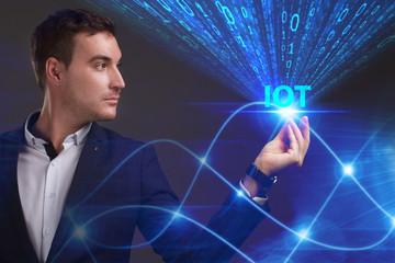 Business, Technology, Internet and network concept. Young businessman working on a virtual screen of the future and sees the inscription: IOT
