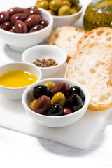 fresh organic olives, spices and bread on white table, vertical