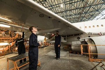 Aircraft maintenance engineers examining aircraft wing 