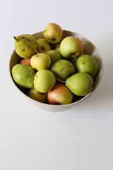 Apples and pears in bowl placed on white table