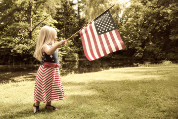 Portrait of happy little girl waving USA flag