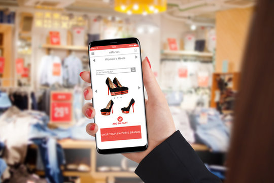 Girl shopping shoes online on her smartphone in clothing store