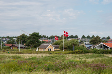Summer homes and Danish flag in front of vacation homes in Karrebaeksminde in Denmark