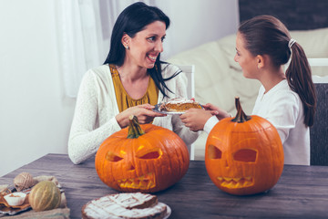 Mother with daughter creating big orange pumpkin for Halloween and having fun