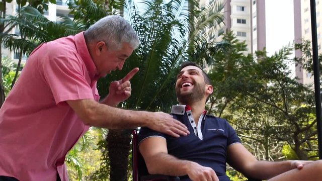 Father Encouraging his Disabled Son in Wheelchair at Park