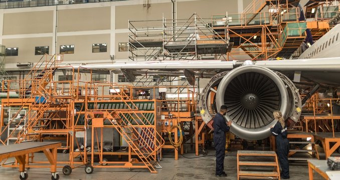 Engineers examining turbine engine of aircraft