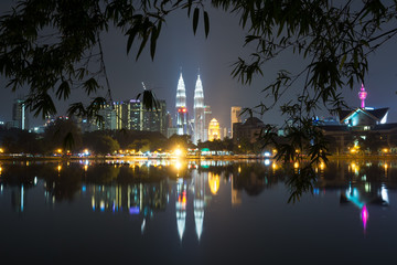 Fototapeta na wymiar Night view of Kuala Lumpur skyline framed by bamboo tree leaves as seen from Taman Tasik Titiwangsa also known as Titiwangsa Lake Garden located in Kuala Lumpur, Malaysia.
