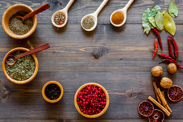 Variety of spices and dry herbs in bowls on wooden kitchen table background top view mock-up