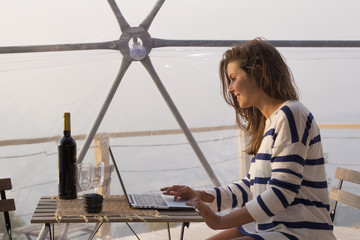 Girl enjoying with a laptop and red wine in a glamping