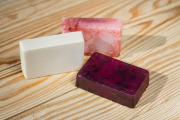 Three handmade rectangular soaps stand on the wood