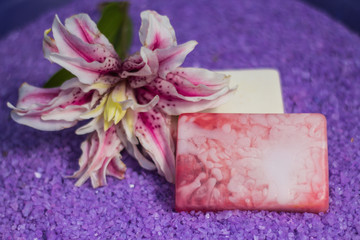 Obraz na płótnie Canvas Two handmeda soaps lay on the lavender sea salt with a lily flower