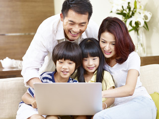asian family with two children using laptop together