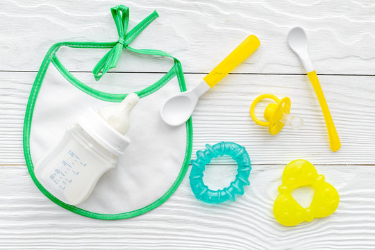 preparation of mixture baby feeding with infant formula powdered milk in bottle with bib on white background top view