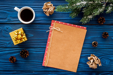 Space for new year greeting. Paper near christmas present and spruce branches on blue wooden background top view mockup