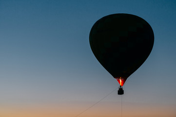Silhouette of flying balloons with people high in sky at twilight. Freedom concept. Romantic recreation. Hot air balls competition. Autumn ballooning festival. Warm weather. Travel and tourism.