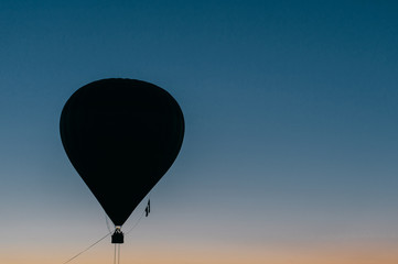 Silhouette of flying balloons with people high in sky at twilight. Freedom concept. Romantic recreation. Hot air balls competition. Autumn ballooning festival. Warm weather. Travel and tourism.