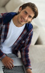 young man working on laptop and looking at camera. view from above