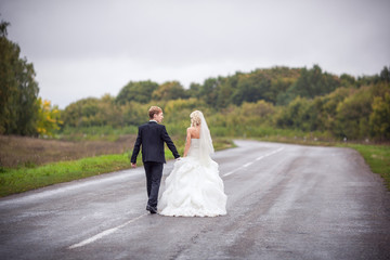 Fototapeta na wymiar Wedding concept. Bride and groom walking on road. One way to future