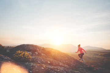 Athletic woman jogging in the mountains enjoying the sunset. Sport tight clothes.  Intentional motion blur.