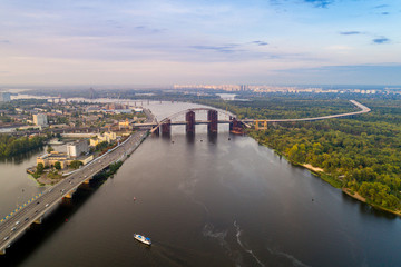 Obraz premium Panoramic view of a modern city with a river, unfinished bridge and park part of the city