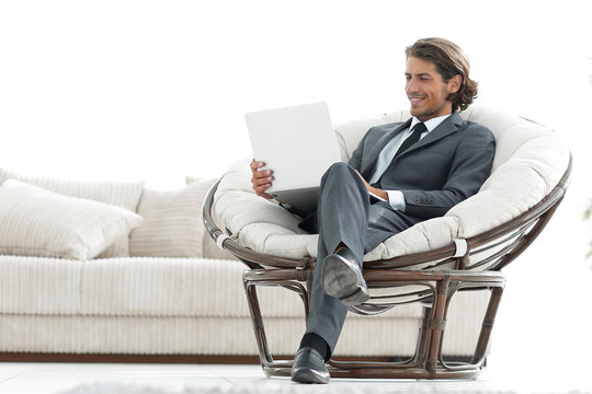 modern businessman with a laptop sitting in a stylish comfortable chair