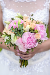 Wedding bouquet of roses and peonies in the hands of the bride