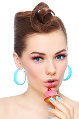Vintage style portrait of young beautiful sexy woman with petit four pastry in her hand