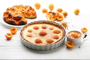 Apricot pies with jam on white wooden table