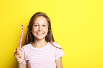 Portrait of beautiful girl with toothbrush on yellow background