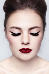 Portrait of young beautiful girl with cat eye make-up and red lips