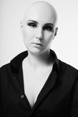 Black and white portrait of young skinhead woman with smoky eyes make-up