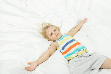 Little boy lying in white bed