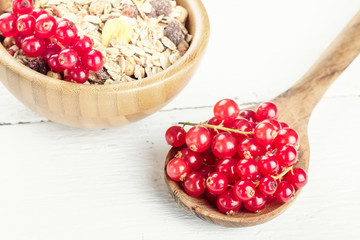 Morning breakfast muesli mix of cereals with redcurrants on wooden table background, selective focus
