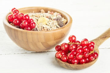 Morning breakfast muesli mix of cereals with redcurrants on wooden table background, selective focus