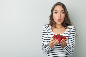 Fototapeta premium Portrait of young woman with strawberries on grey background