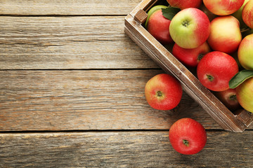 Ripe apples in crate on grey wooden table