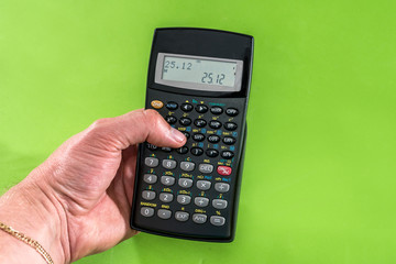 hand holding digital calculator isolated on green