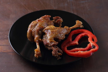 Fried meat with red bell pepper on a black plate for a restaurant