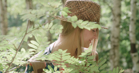 Portrait of beautiful caucasian woman in a forest wearing hat and backpack. Adventure, travel, tourism and leisure concept -  smiling girl relaxing by the lake in woods.