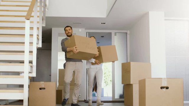 Happy Couple Move Boxes with Stuff into Their New Bright and Modern House. A lot of Boxes Already Stand in the Room. Shot on RED EPIC-W 8K Helium Cinema Camera.
