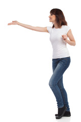 Smiling Woman In Jeans And White T-shirt Is Presenting. Side View.