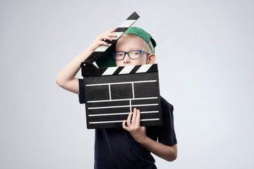 boy in green hat holding clapper board in hands.