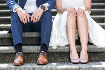 Brautpaar sitzt auf Treppe und zeigt Schuhe, Beine und Hände
